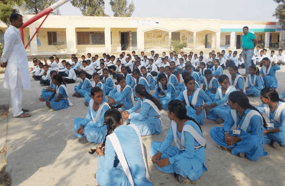 Indian students standing together during a school morning assembly while listening to a thought of the day in Hindi and English